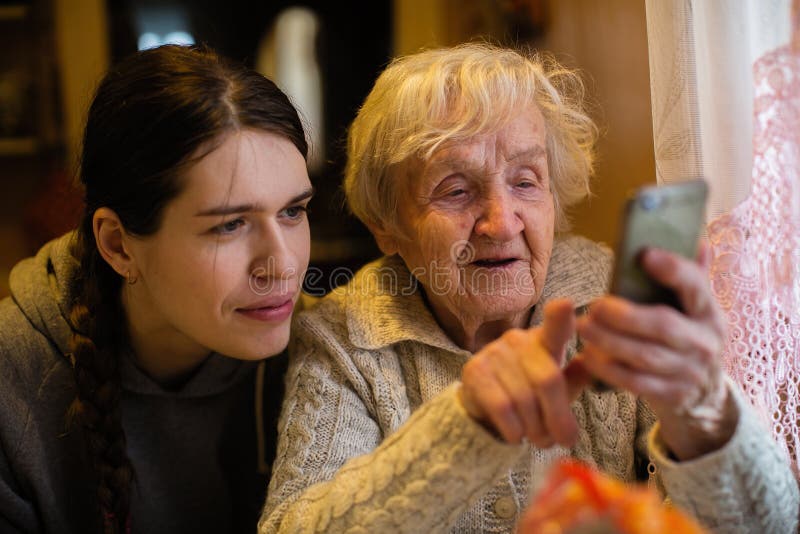 Een oude dame bekijkt een smartphone, met zijn volwassen kleindochter hulp Ð˜Ñ  Ñ ‚Ð ¾ Ñ ‡ Ð ½ Ð¸Ðº:  Online u